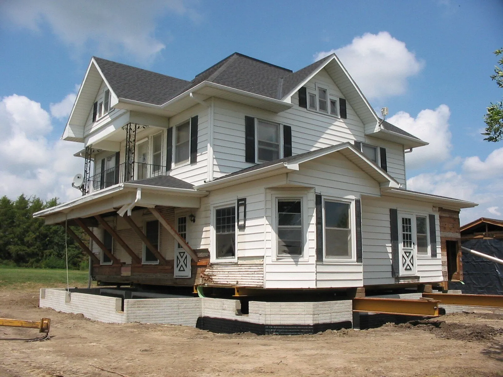 White two-story house raised on steel beams above a new block foundation